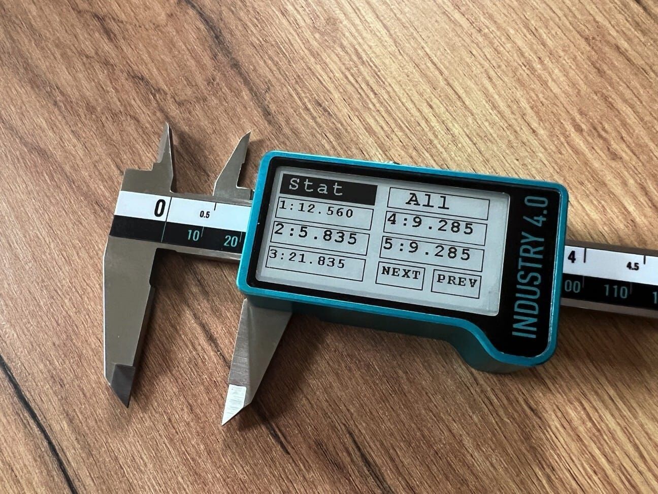 Microtech Metrology Digital Präzisionsmessschieber 300mm: Auf Holztisch liegend, E-Ink Display zeigt Messwerte