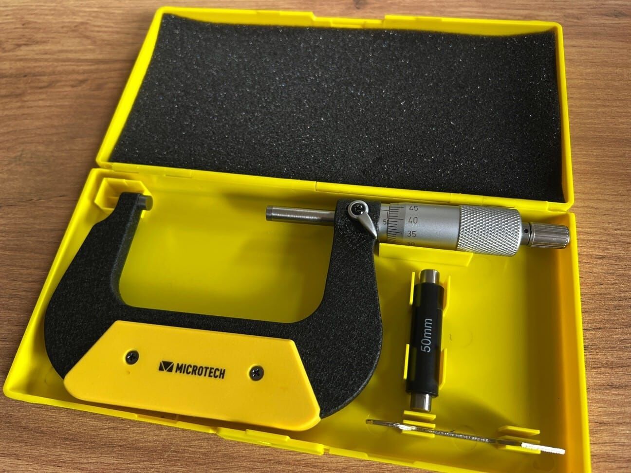 Microtech 60-75mm Messschraube: Offener gelber Koffer mit schwarzem Schaumstoff und Messdorn