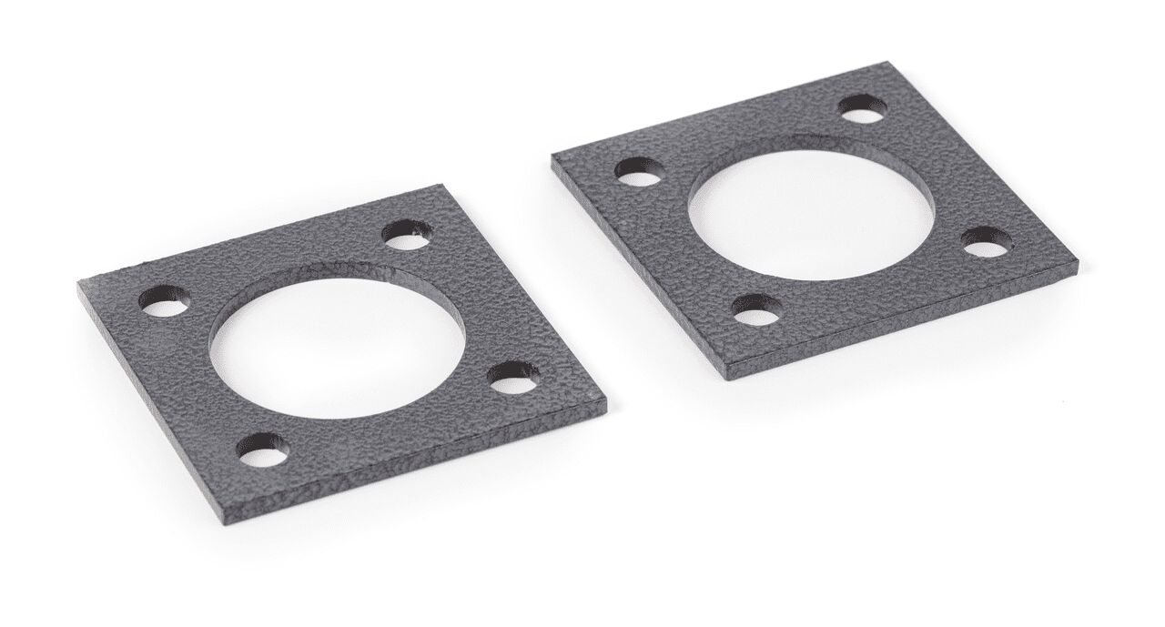 Zwei schwarze Fußplatten auf weißem Hintergrund. Die Platten sind quadratisch und haben ein großes Loch in der Mitte. Vier kleinere Löcher an den Ecken ermöglichen ein sicheres Anbringen der Platten.