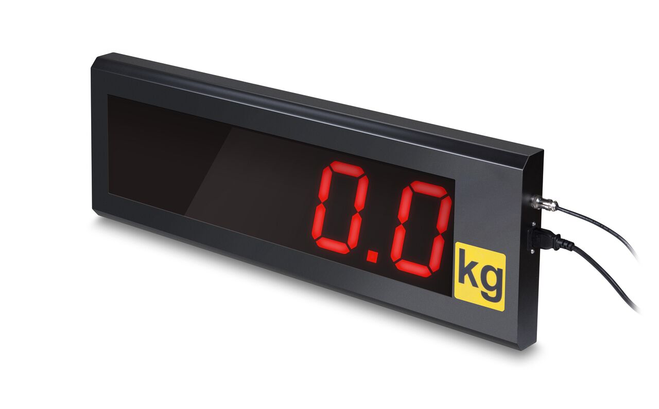 Schwarze Anzeige auf weißem Hintergrund. Die Zahlen auf der Anzeige sind rot, mit einem gelben Aufkleber mit der Aufschrift "kg". Zwei Kabel ragen auf der Seite raus.
