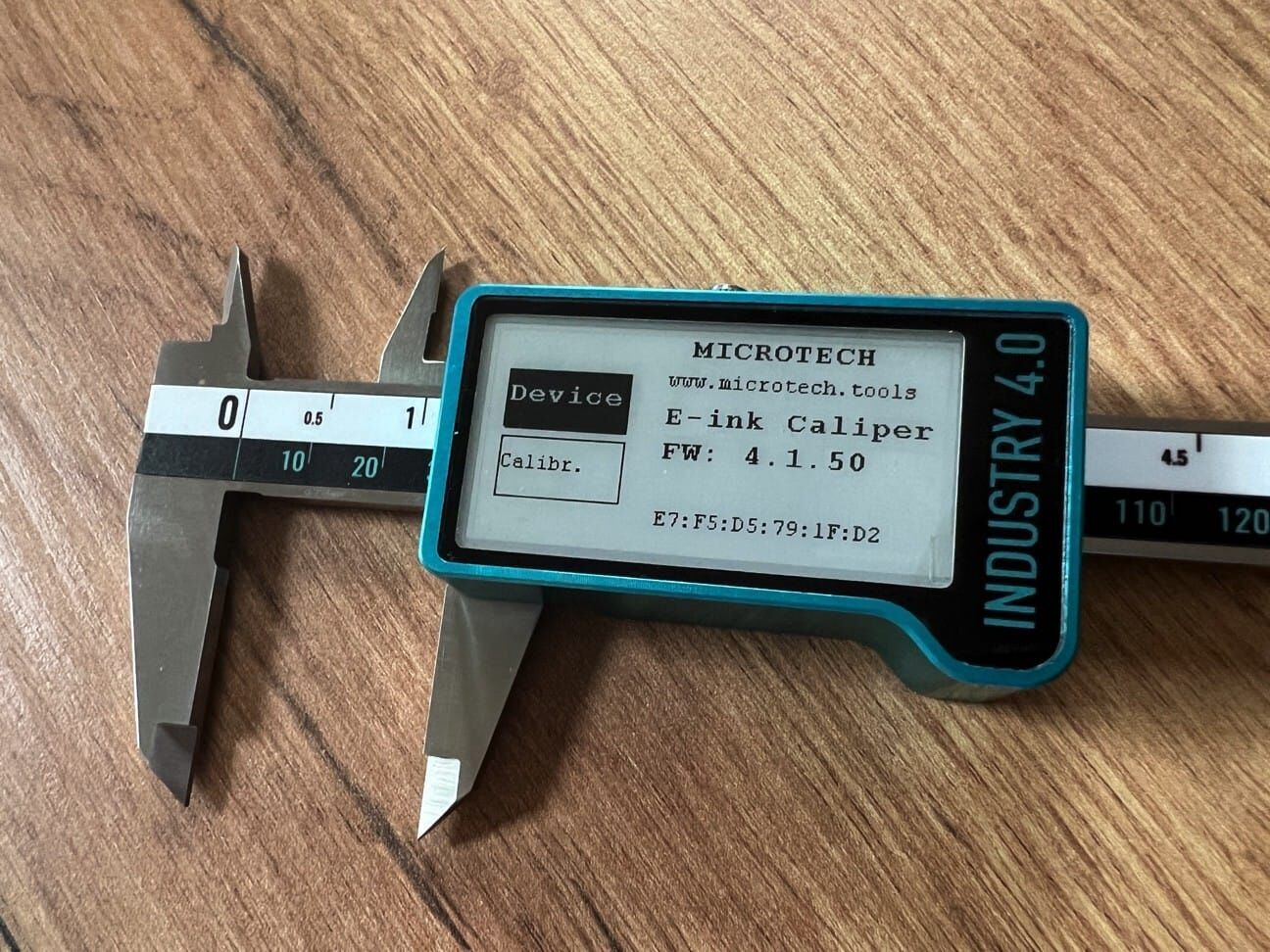 Digitaler Präzisionsmessschieber E-Ink: Metallmessschenkel, türkises Gehäuse mit Display, auf Holzuntergrund