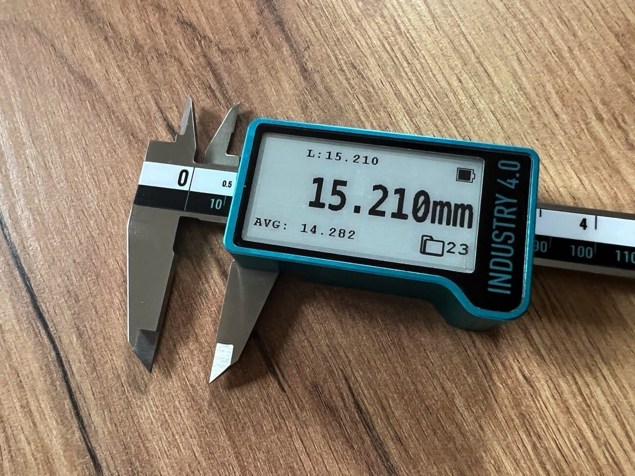 Microtech Metrology Präzisionsmessschieber 141093030B: E-Ink Display zeigt 15.210mm in Frontalansicht auf Holzuntergrund