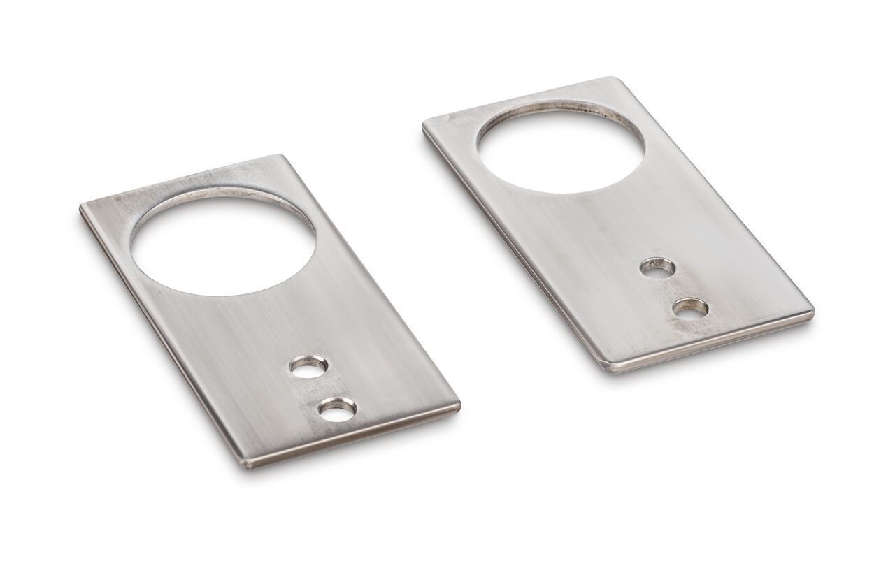Fußplatten Paar aus Edelstahl auf weißem Hintergrund. Die Fußplatten sind rechteckig und haben ein großes und zwei kleine Löcher.