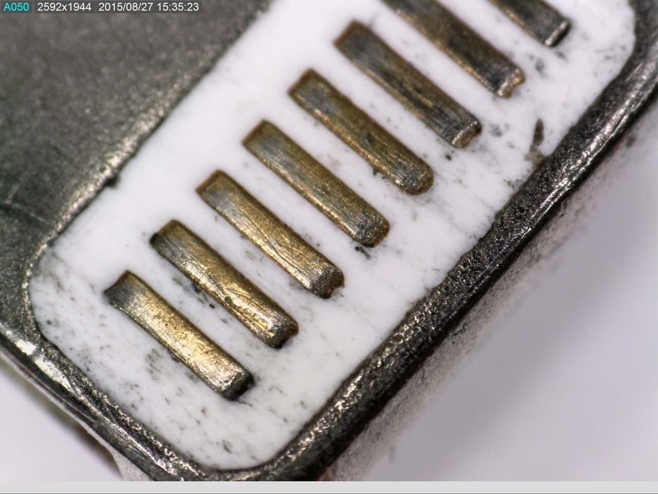 AM7515MZTL USB-Mikroskop - Nahaufnahme goldener Kontaktstifte auf weißer Oberfläche, leicht verschmutzt