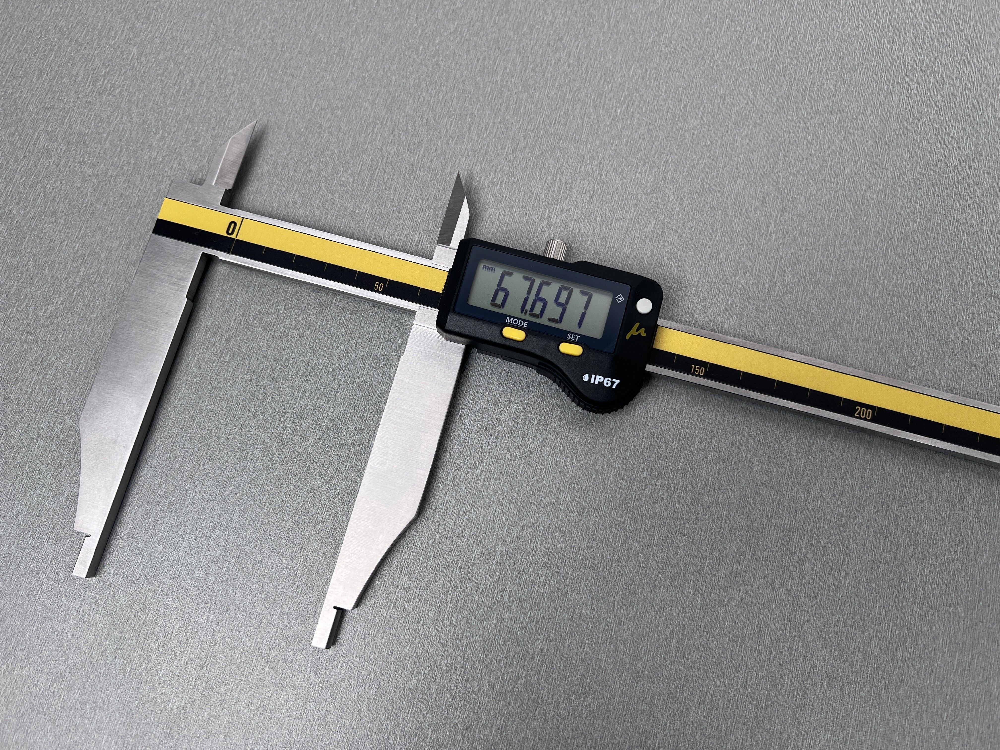 Microtech Digitaler Präzisionsmessschieber 500mm, IP67. Frontalansicht der Edelstahlzangen mit gelbem Lineal und Anzeige.