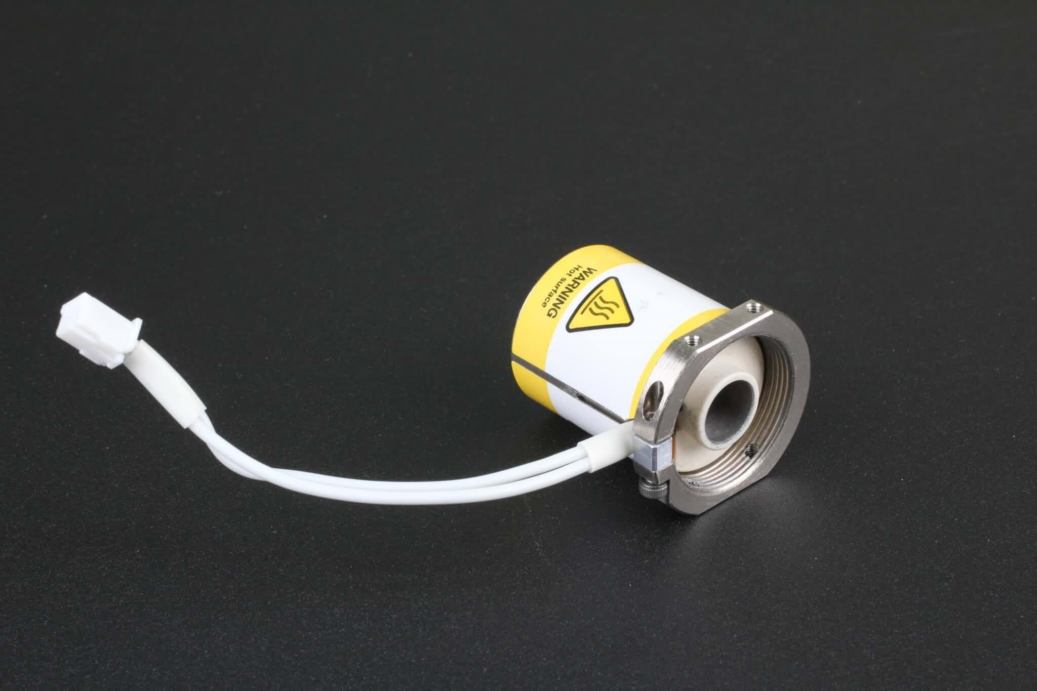 Magnetventil auf schwarzem Hintergrund. Das Ventil besteht aus einem runden Körper aus dem ein weißes Kabel ragt. Der Körper ist weiß und gelb und weißt ein Warnzeichen auf.
